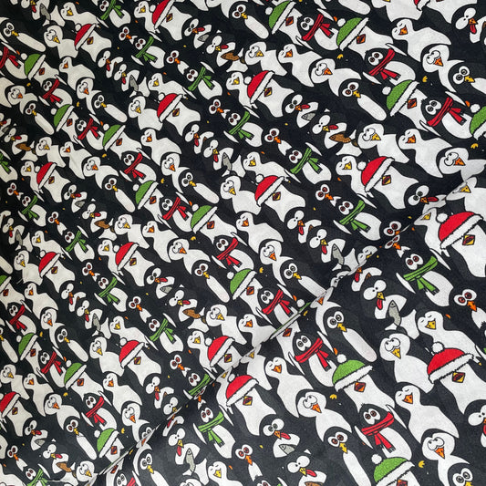 Pattern of cartoon penguins wearing Christmas hats and scarves on a black background.