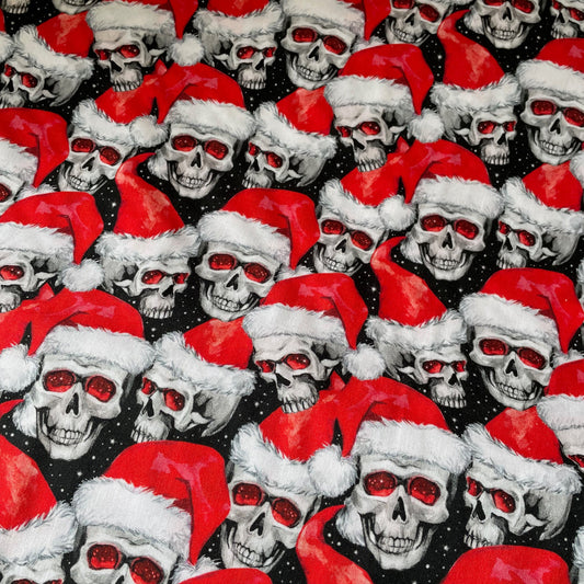 Pattern of skulls wearing red Santa hats on a black background