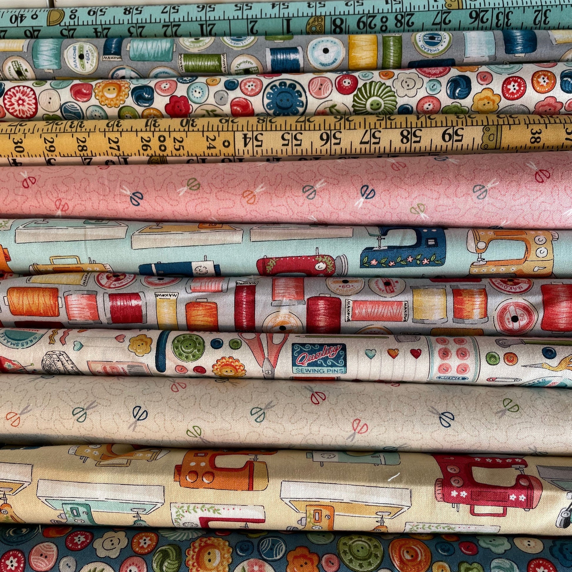 Collection of fabric rolls with sewing-themed patterns and a measuring tape.