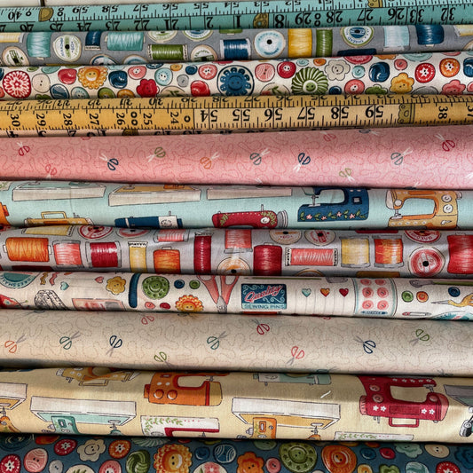 Collection of fabric rolls with sewing-themed patterns and a measuring tape.