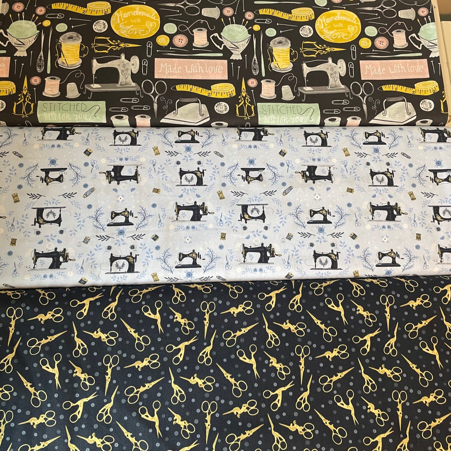 Three fabric swatches with sewing-themed patterns including sewing machines, scissors, and other tools.